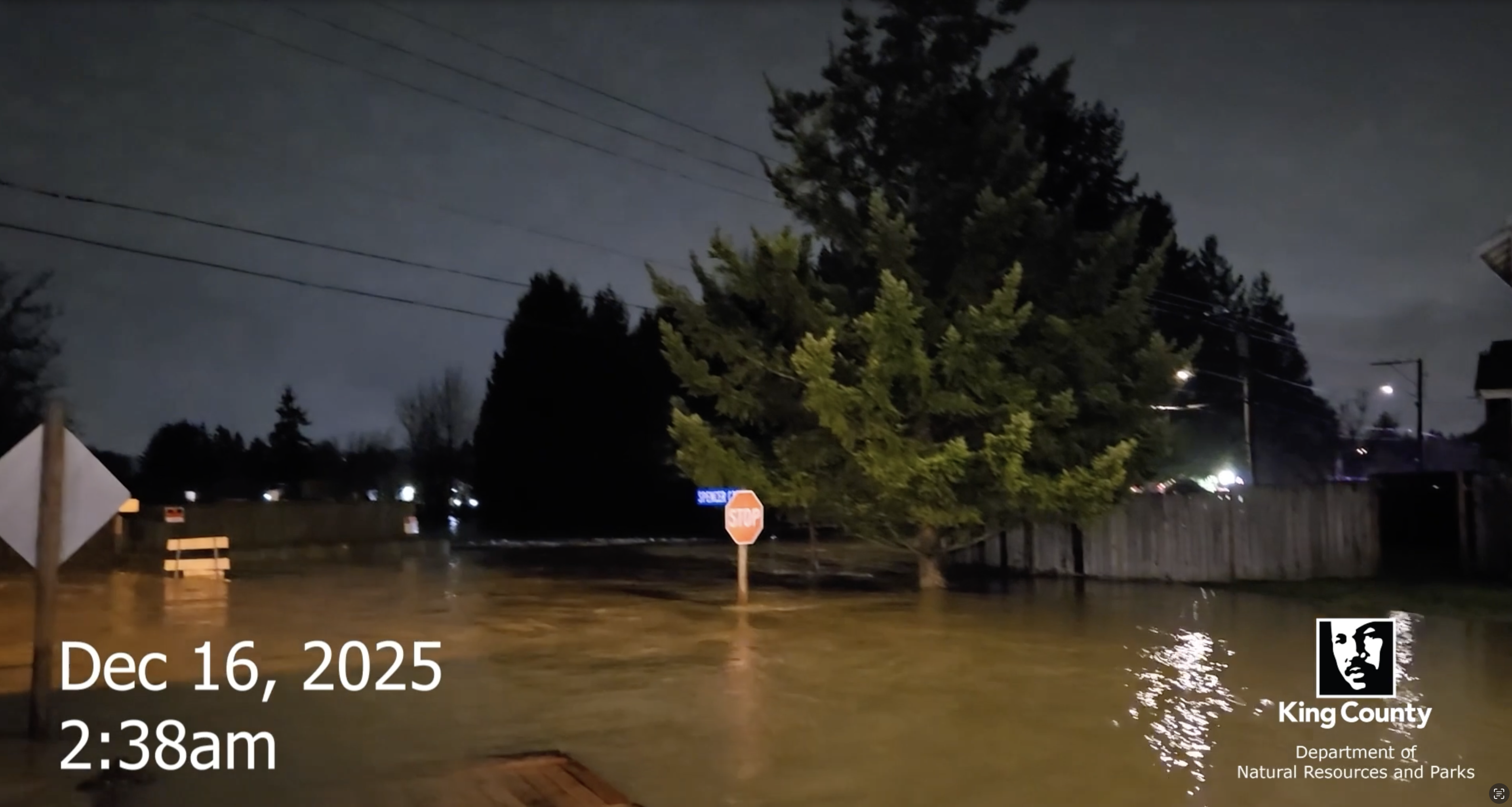 Flooding at night on the White River, street signs are partially submerged in brown water. Dec. 16 2025 2:30 a.m..