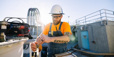 A person in a hard hat repairs equipment at a treatment plant
