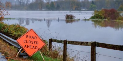 A "Road Closed Ahead" sign next to a flooded field.