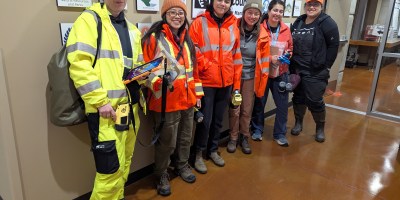 Six King County flood responders in safety gear pose indoors before a Flood Patrol shift.