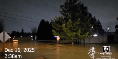 Flooding at night on the White River, street signs are partially submerged in brown water. Dec. 16 2025 2:30 a.m..